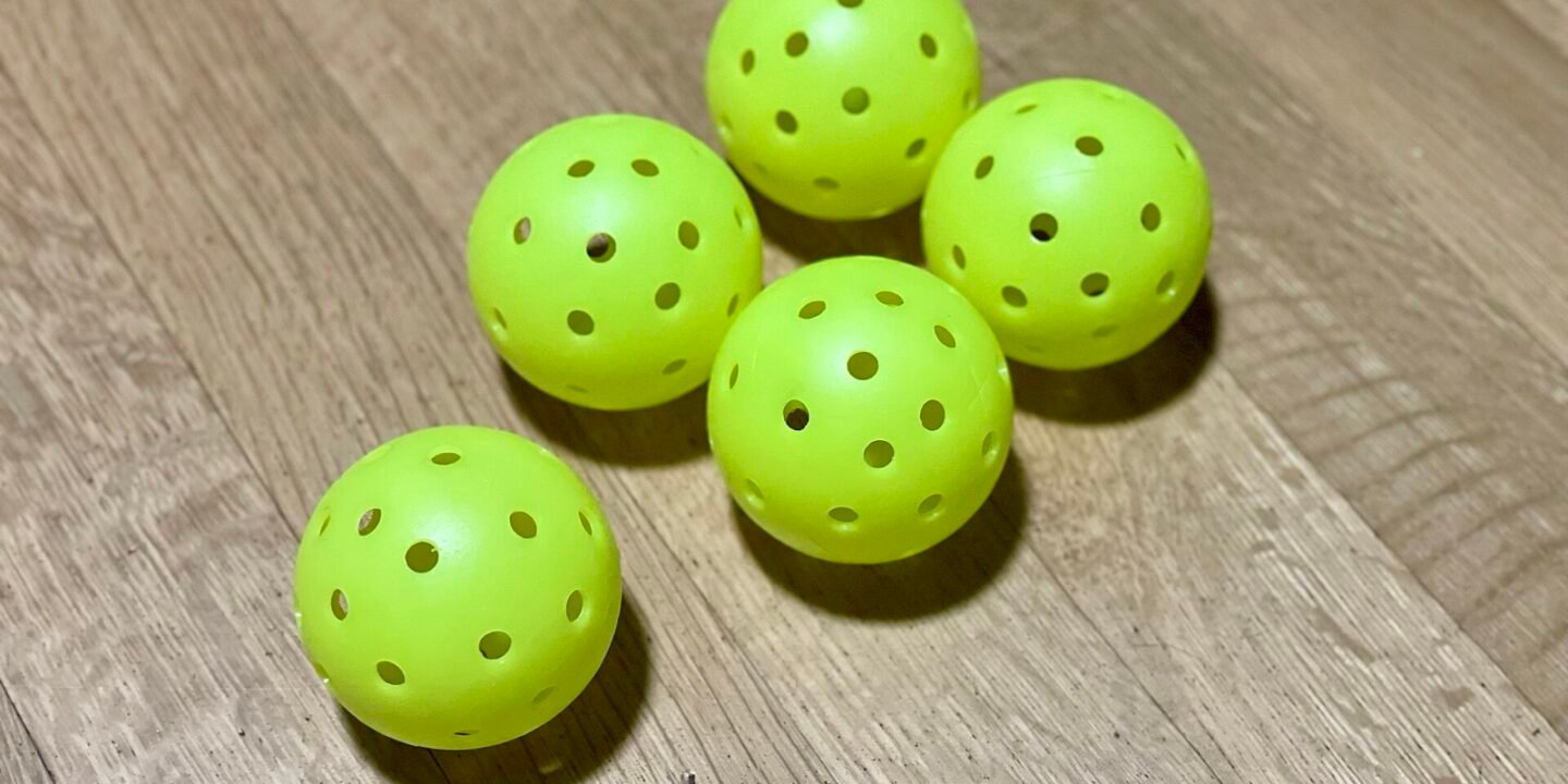 indoor and outdoor pickleballs side by side showing the difference in hole size and hole count
