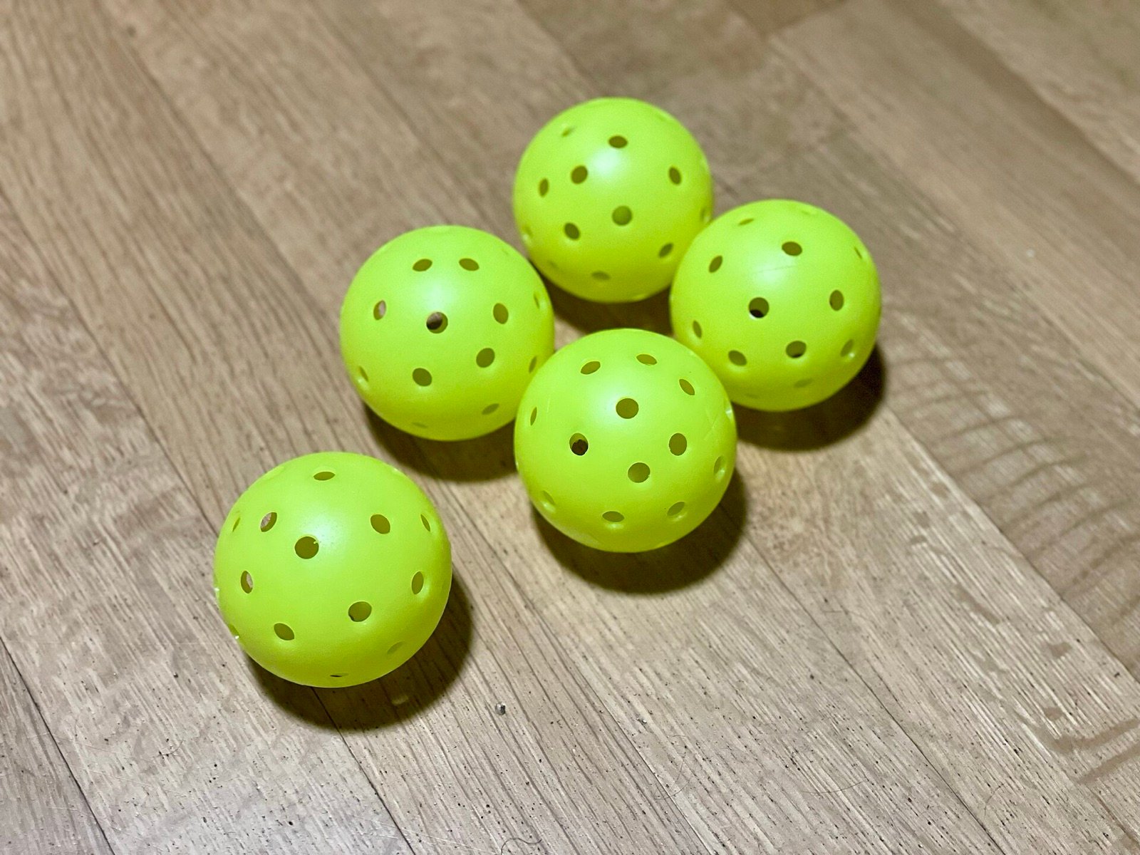 indoor and outdoor pickleballs side by side showing the difference in hole size and hole count