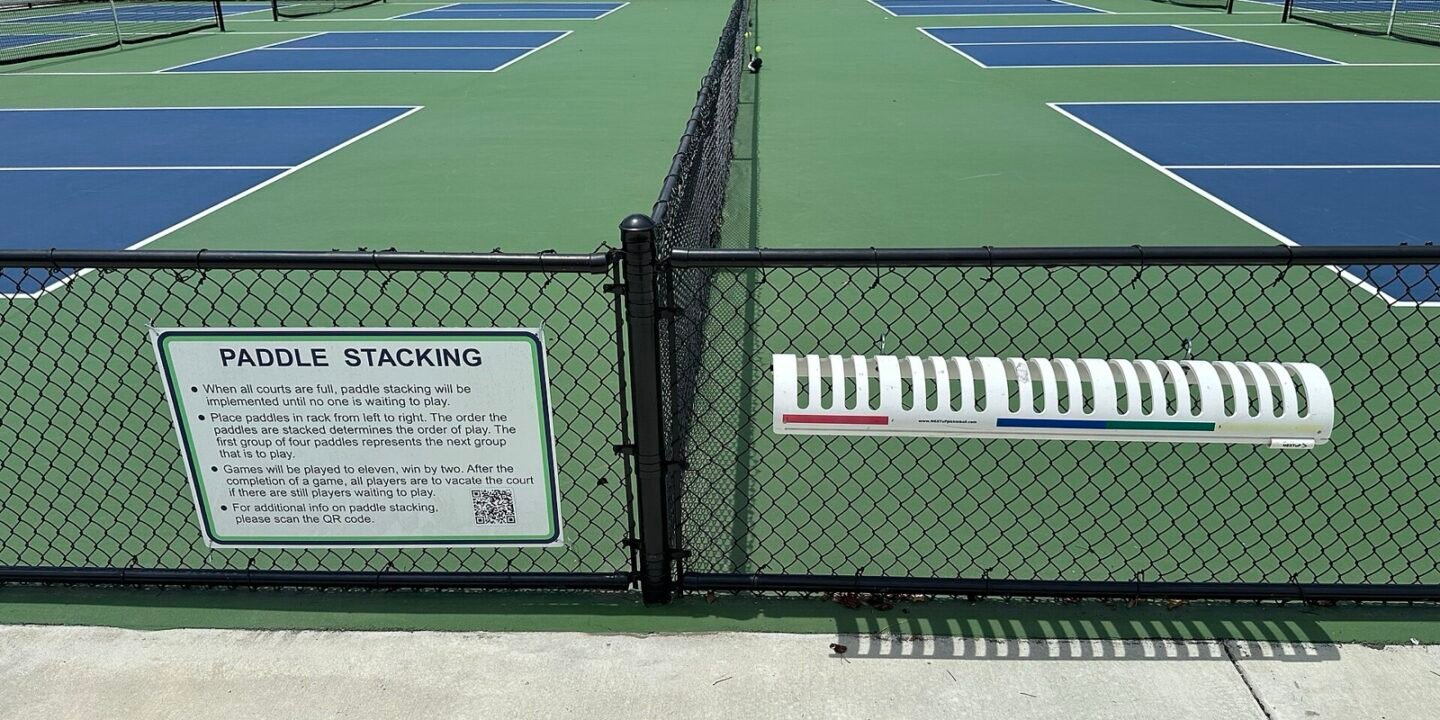 rack of pickleball paddles stacked courtside showing the range of shapes and weights players choose from