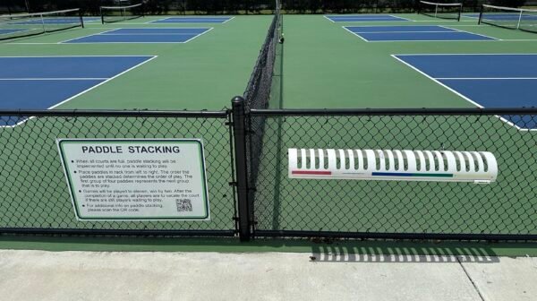 rack of pickleball paddles stacked courtside showing the range of shapes and weights players choose from