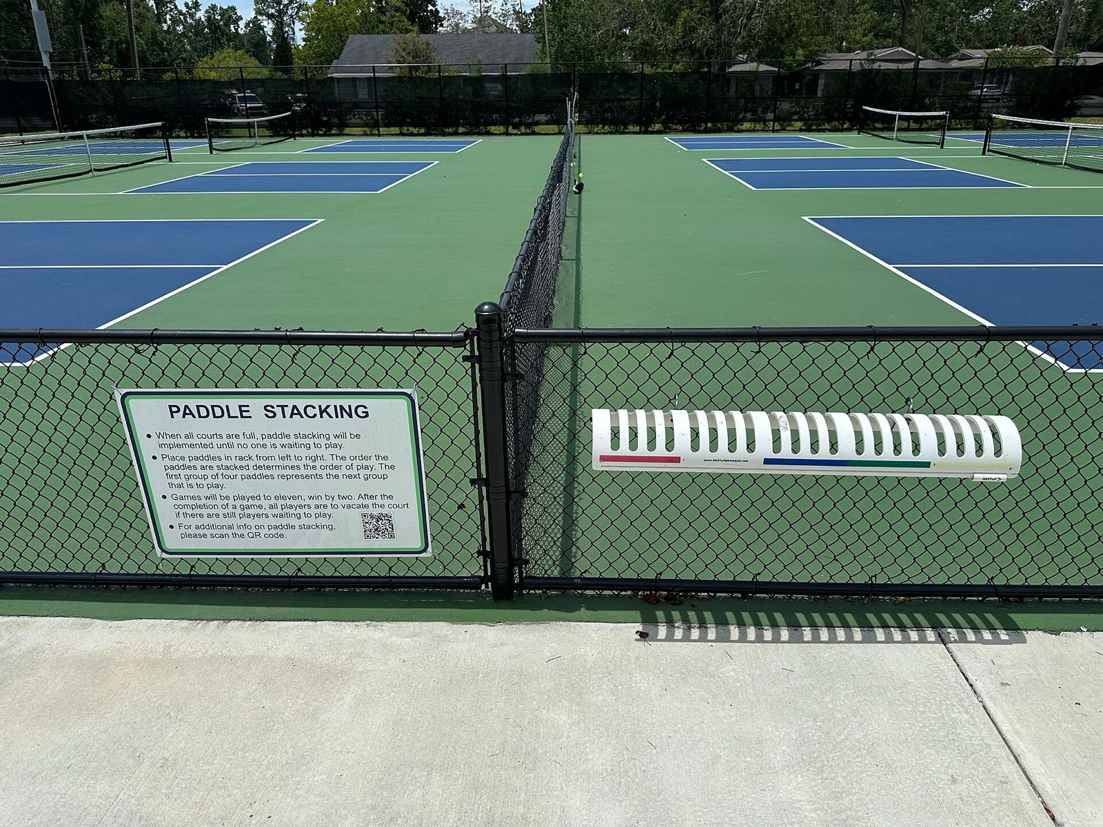 rack of pickleball paddles stacked courtside showing the range of shapes and weights players choose from