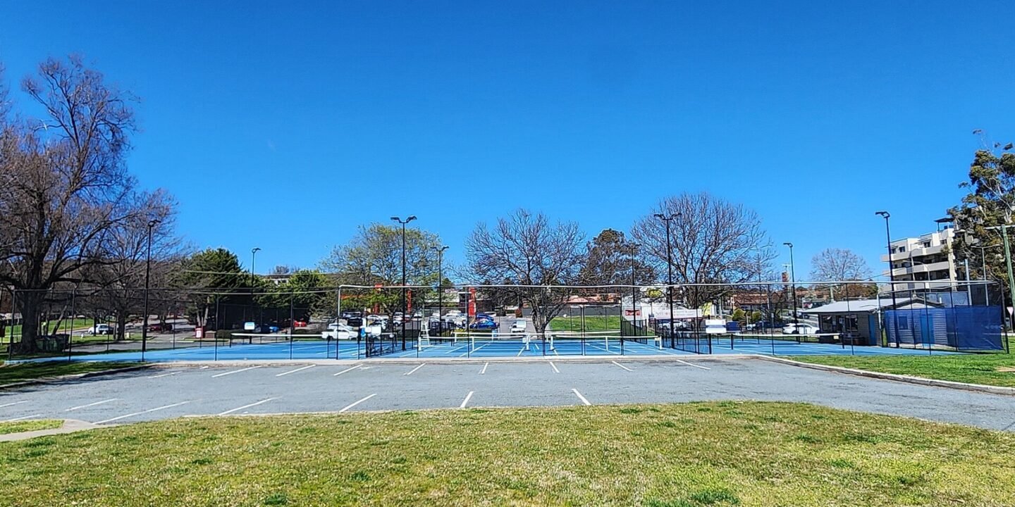 a tennis court overlaid with pickleball lines and a portable net set up for a game