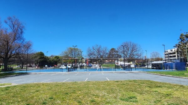 a tennis court overlaid with pickleball lines and a portable net set up for a game