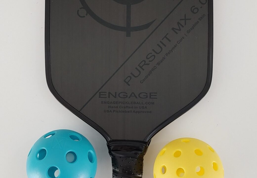 a pickleball paddle laid beside two outdoor pickleballs, the core contents of a basic pickleball set
