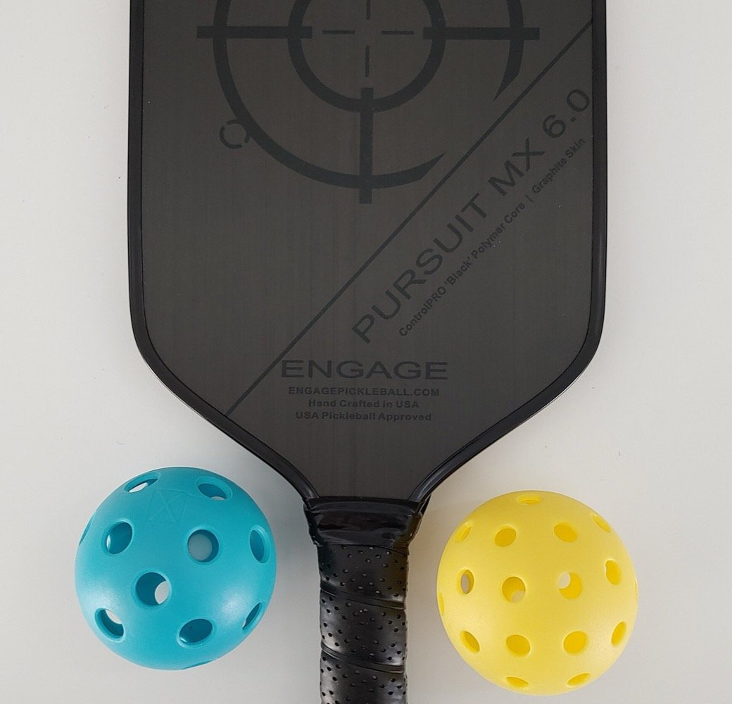a pickleball paddle laid beside two outdoor pickleballs, the core contents of a basic pickleball set